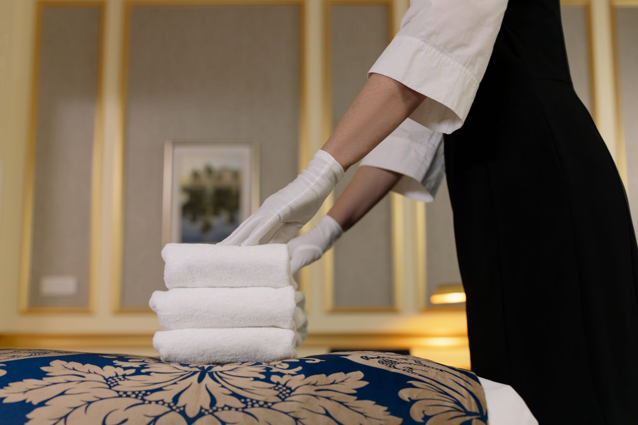 vision A hotel housekeeper neatly stacks fresh towels in a luxurious room setting.